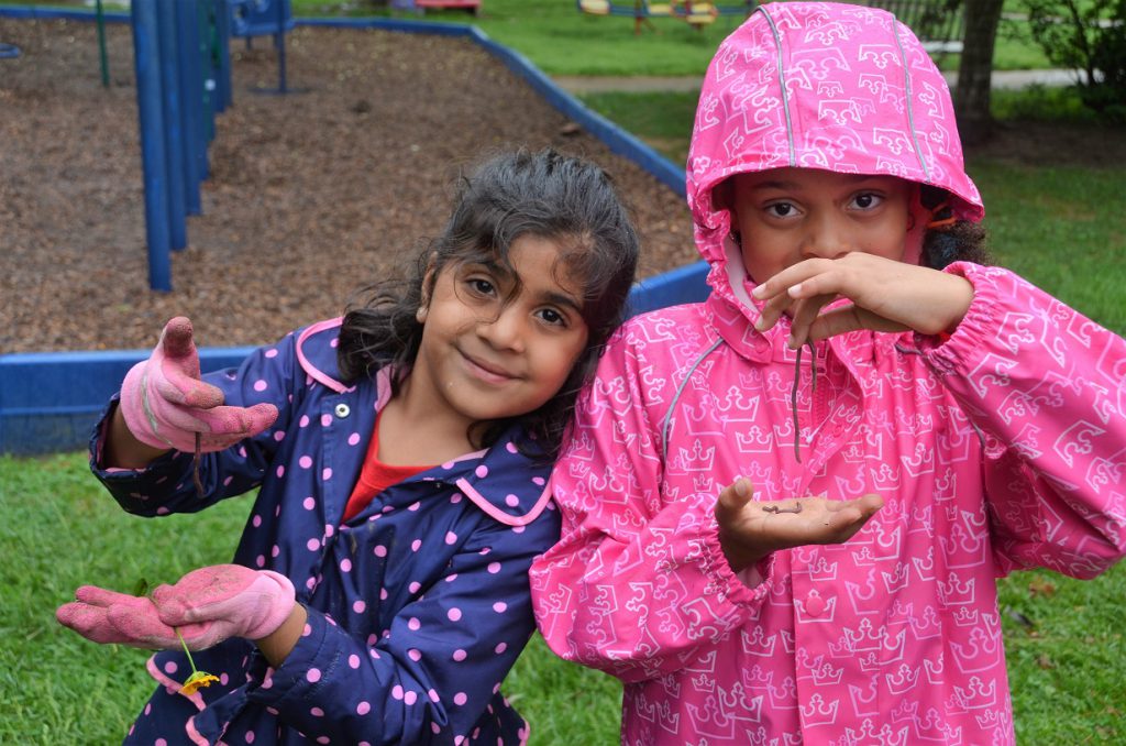 Two elementary girls holding earthworms on a rainy day