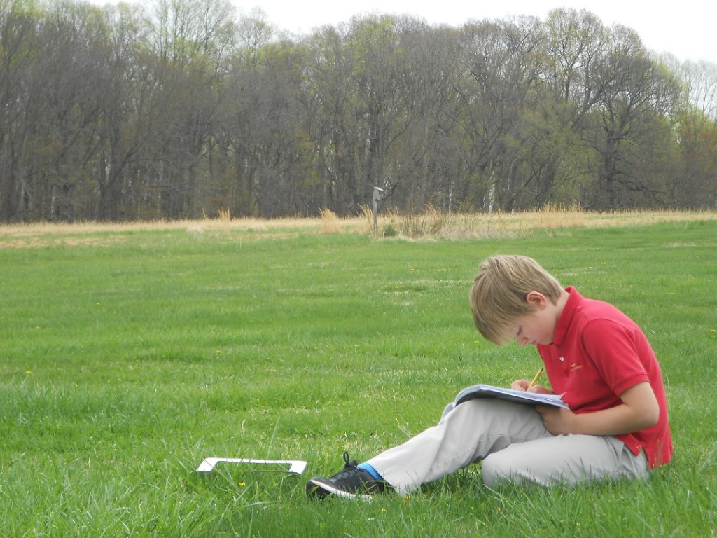 Elementary student writing observations of nature in a journal