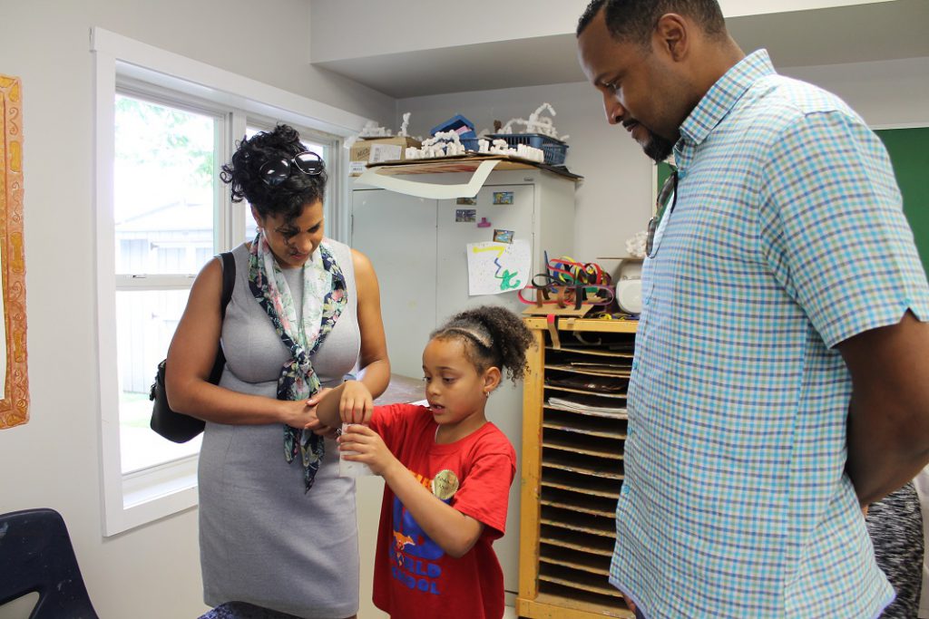 Elementary student showing artwork to parents