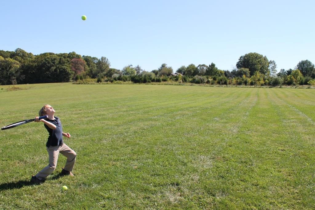 Elementary student practicing tennis serve outside in physical education class