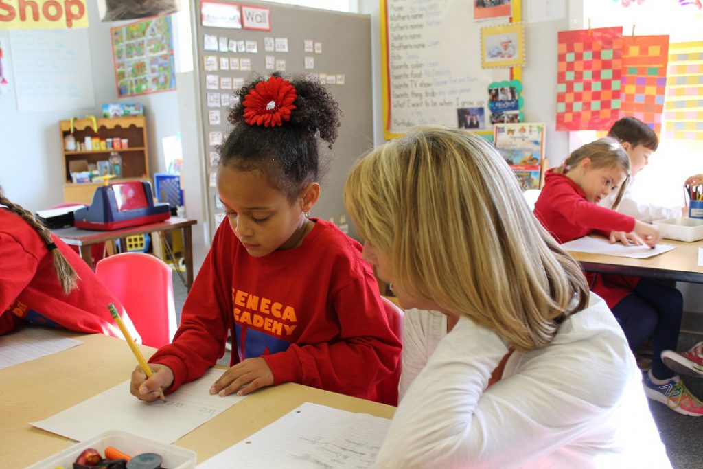 Teacher assisting elementary girl with handwriting