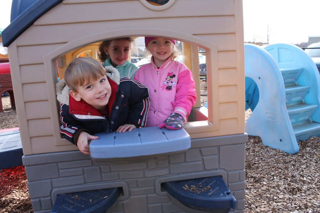 Preschool students in a play house outside