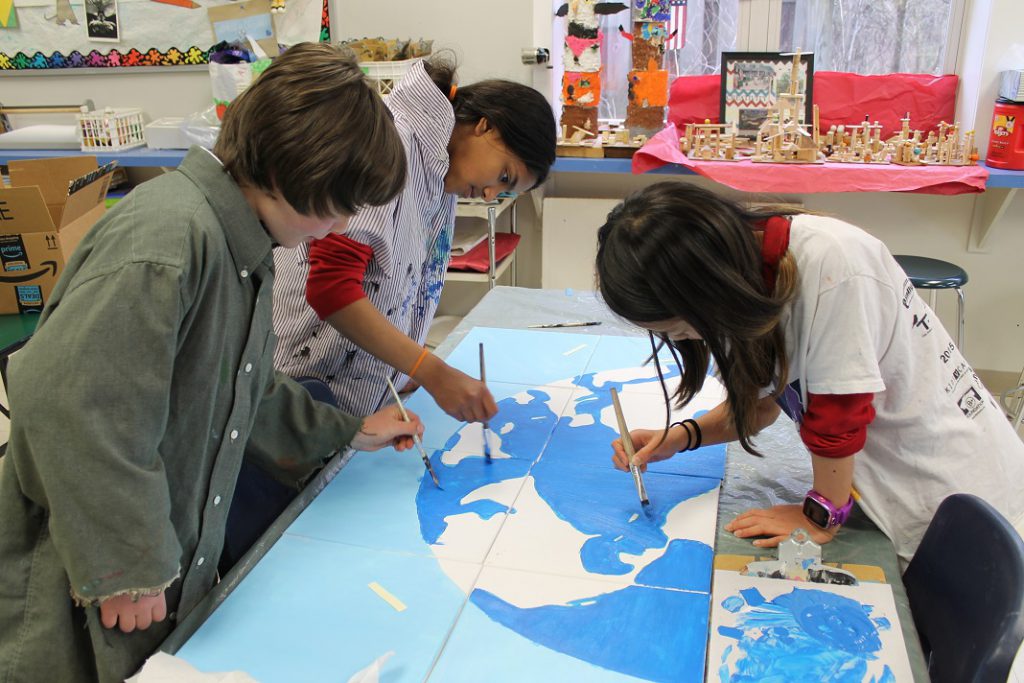 Elementary students in art class painting a map of the world