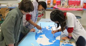 Elementary students painting a map of the world